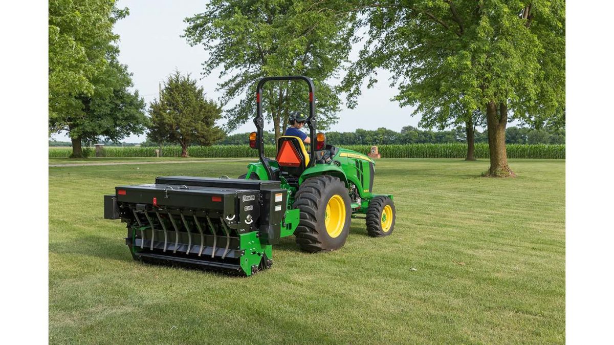 A Frontier GS1160 Overseeder with a John Deere 3039R Compact Utility Tractor over seeding a large lawn.